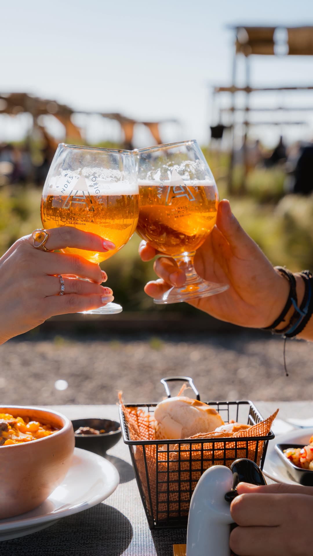 Dos copas brindando al sol, con una mesa servida adelante