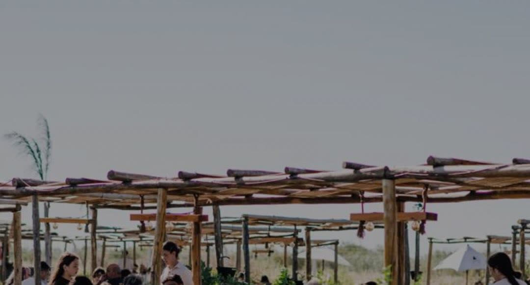 Pérgolas de madera con gente almorzando bajo el cielo abierto