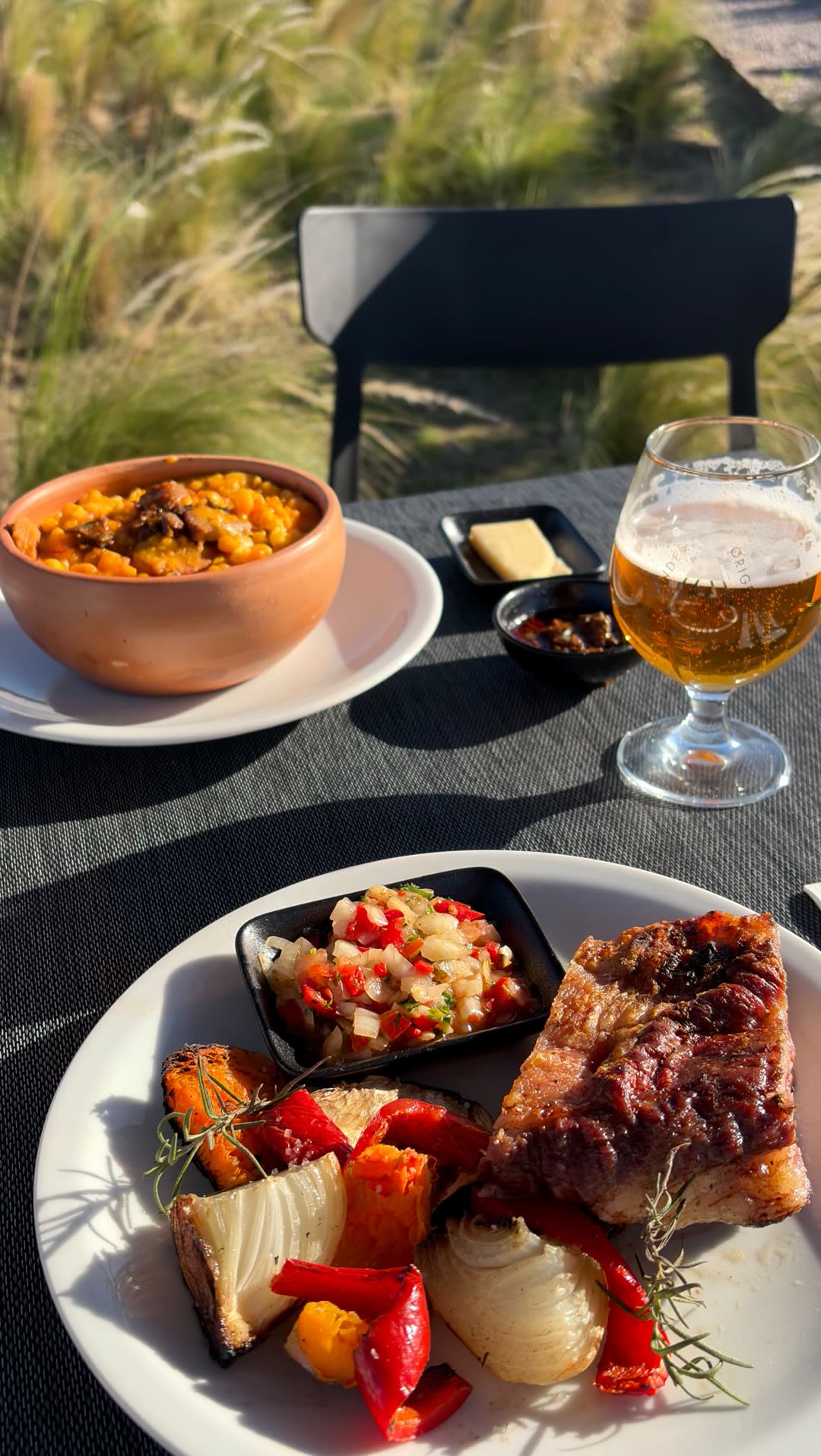 Plato con carnes y verduras asadas y una cerveza